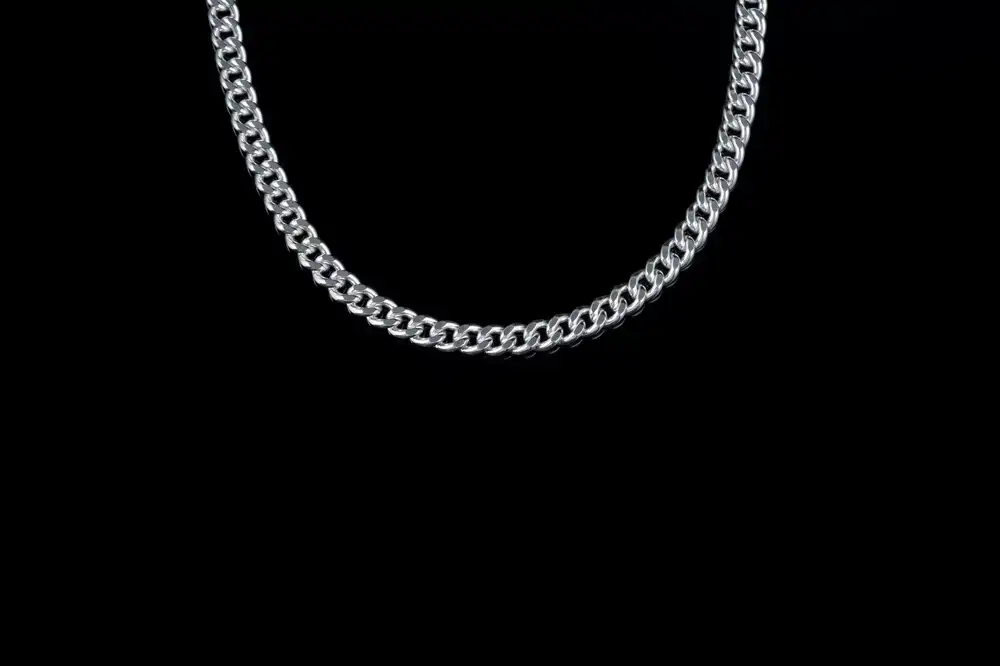 Hands carefully polishing a silver necklace chain