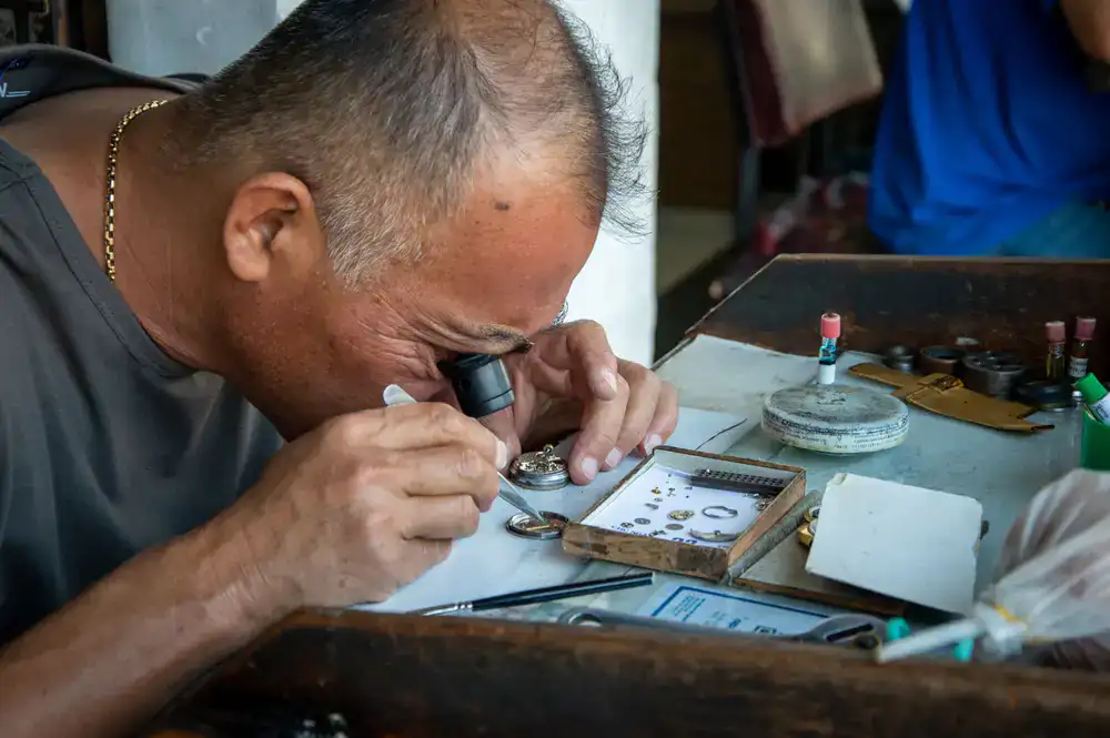 Silversmith carefully inspecting a silver ring for repairs